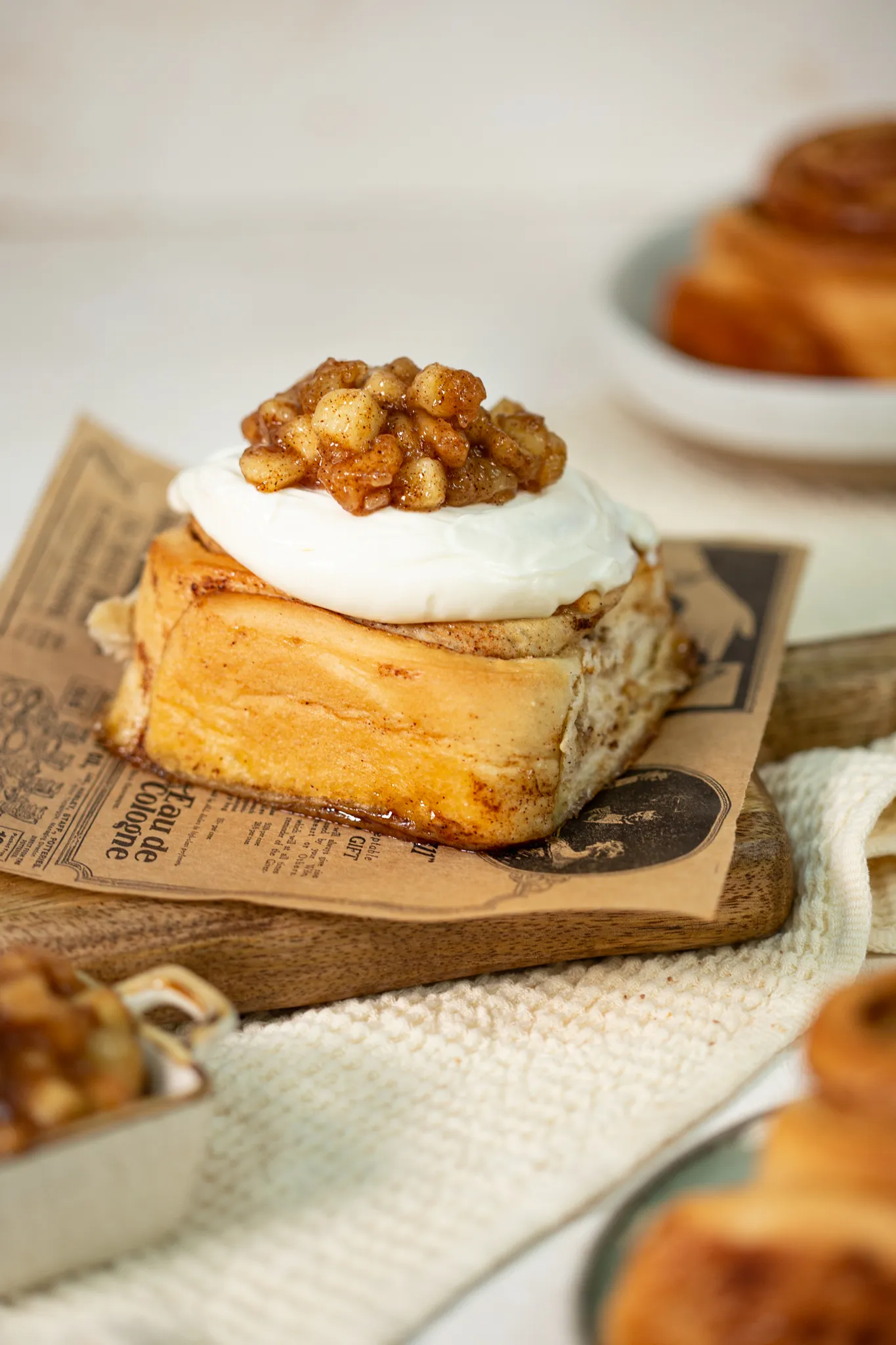 Rollo de canela con glaseado y trozos de manzana, sobre papel de periódico