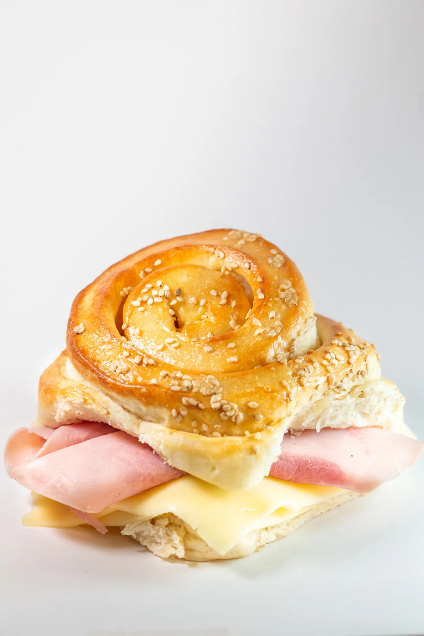Rollo de pan brioche con sésamo, relleno de jamón y queso