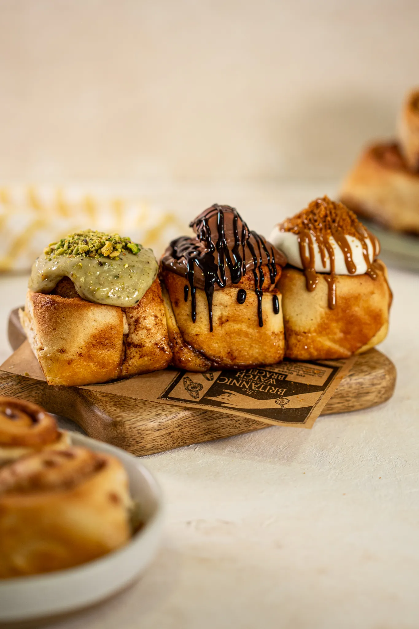 Tres rollos de canela con pistacho, chocolate y caramelo sobre una tabla de madera